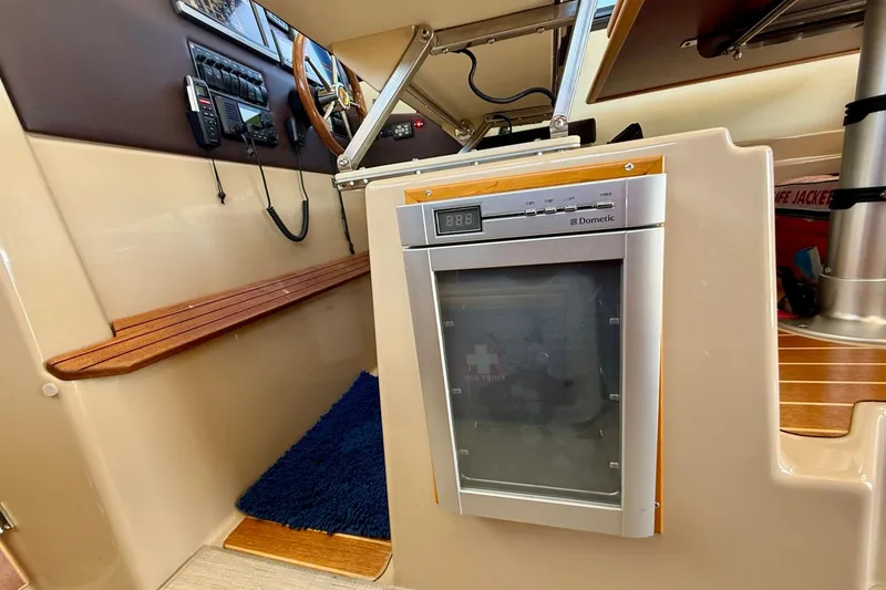 Slide: The Image of Interior of a 2015 Cutwater C-30 CB boat featuring a Dometic fridge and control panel. - 27