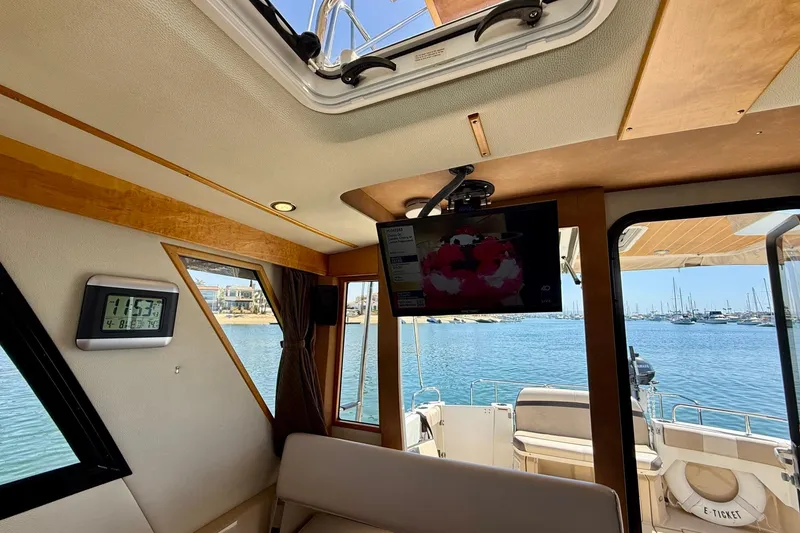 Slide: The Image of Interior view of 2015 Cutwater C-30 CB boat with TV, clock, and marina backdrop. - 30
