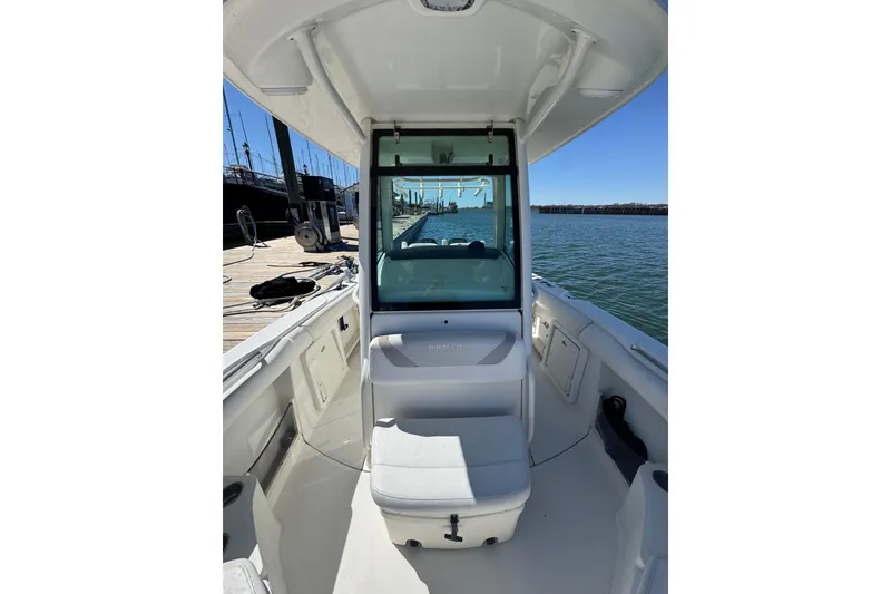 Slide: The Image of 2014 Boston Whaler 280 Outrage boat interior at dock, showcasing seating and helm area. - 2