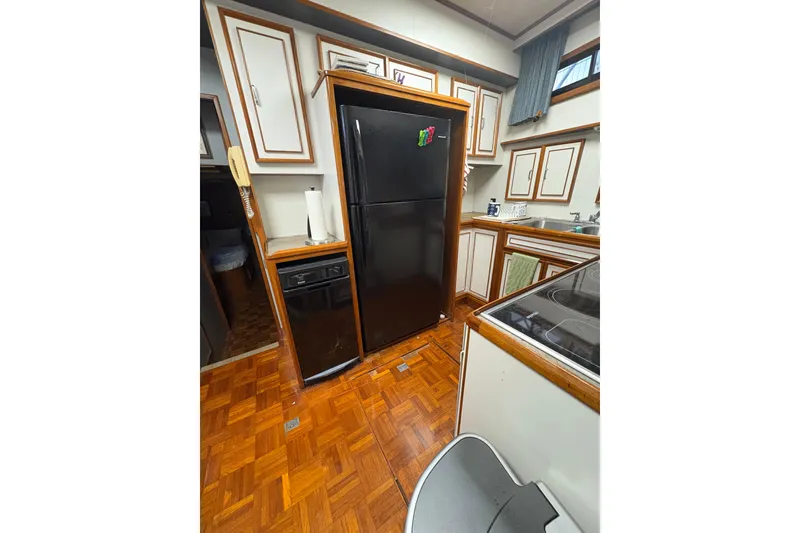 Slide: The Image of Kitchen area of 1989 Jefferson 60' Marquessa Motor Yacht with wood flooring and black appliances. - 16