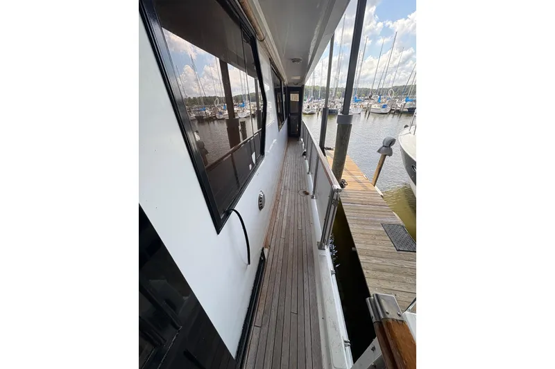 Slide: The Image of Side deck of 1989 Jefferson 60' Marquessa Motor Yacht at marina, showcasing wooden walkway. - 3