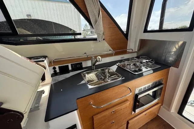 Slide: The Image of Kitchen area of 2026 Cutwater C-288 Coupe with stove, sink, and microwave. - 23