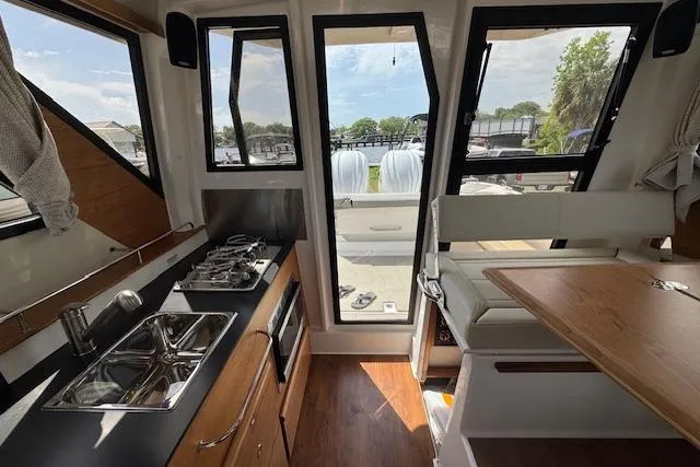 Slide: The Image of Interior of 2026 Cutwater C-288 Coupe featuring kitchen and dining area with outdoor view. - 24