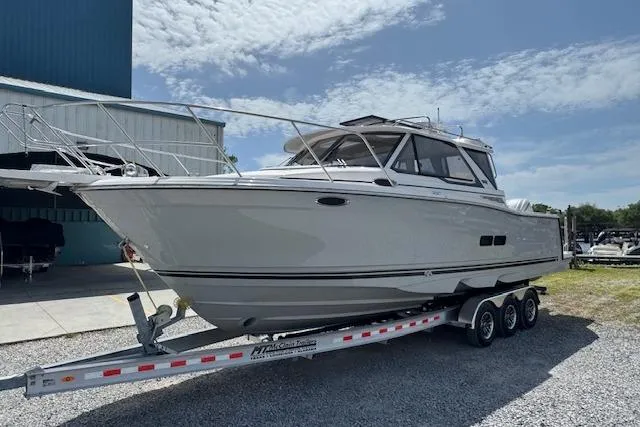 Slide: The Image of 2026 Cutwater C-288 Coupe boat on a trailer, parked outdoors under a partly cloudy sky. - 4