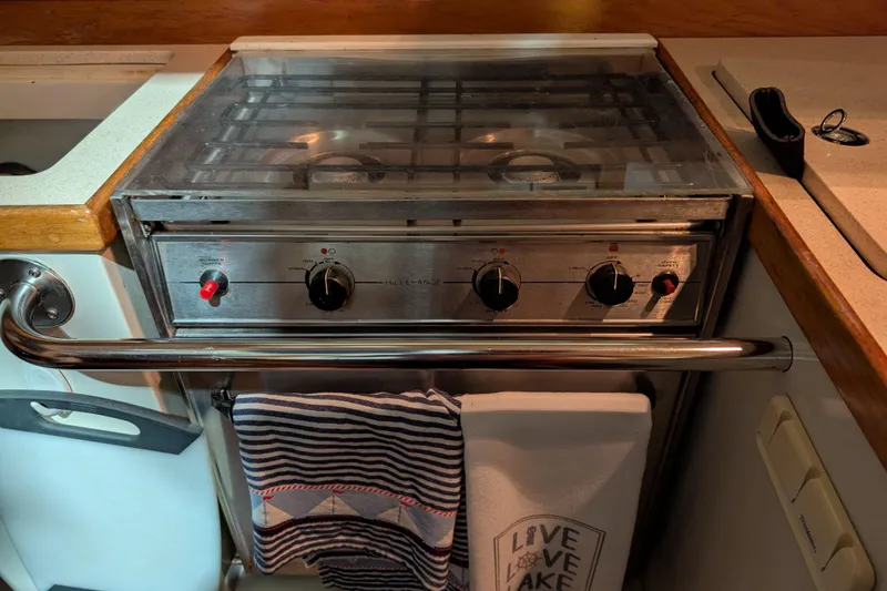 The Image of Galley stove in 1995 Catalina 36 MkII sailboat, with striped towel and "Live Love Lake" cloth. - 1