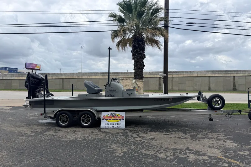 Slide: The Image of 2018 SCB Stingray boat on trailer, parked near a palm tree under cloudy skies. - 0