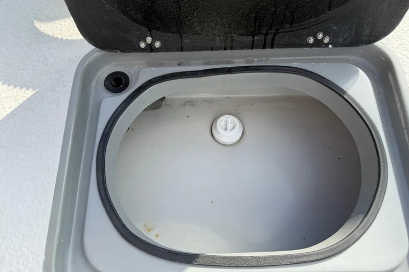 Slide: The Image of Open storage compartment on 2018 SCB Stingray boat, featuring a circular drain plug. - 18
