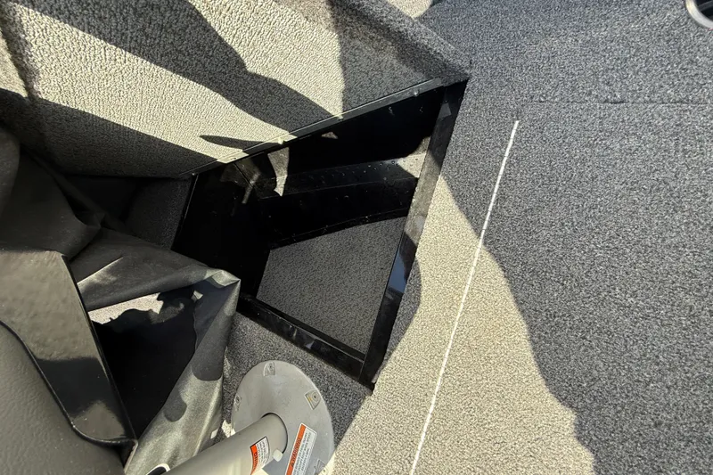 Slide: The Image of Interior view of a 2021 Lund 1650 Rebel XL Sport boat, showcasing carpeted flooring and storage compartment. - 8