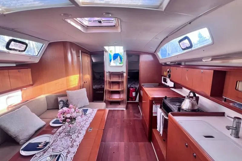 Slide: The Image of Interior of a 2009 Beneteau Oceanis 40 sailboat, featuring a cozy dining area and kitchen. - 22