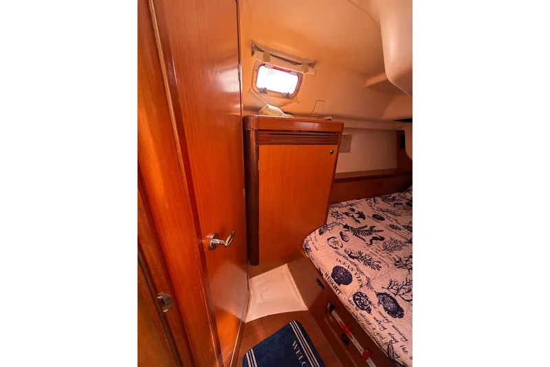 Slide: The Image of Interior cabin of 2009 Beneteau Oceanis 40 sailboat with wooden cabinetry and nautical-themed bedding. - 41