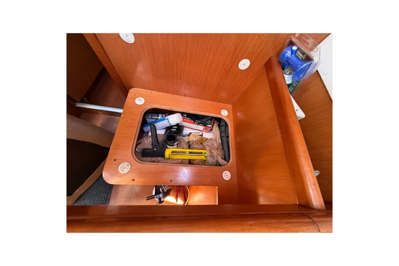 Slide: The Image of Storage compartment inside a 2009 Beneteau Oceanis 40 sailboat, containing various tools and supplies. - 44
