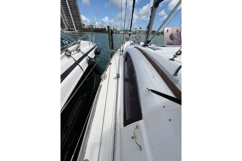 Slide: The Image of 2009 Beneteau Oceanis 40 sailboat docked beside another vessel, clear sky background. - 60