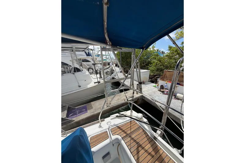 Slide: The Image of 2009 Beneteau Oceanis 40 sailboat docked, featuring a blue canopy and wooden deck. - 80