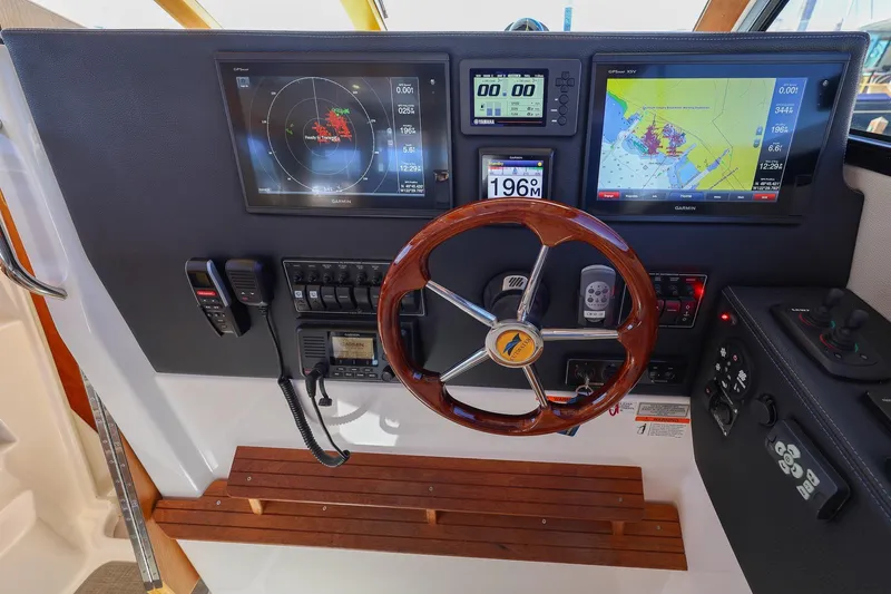 Slide: The Image of 2019 Cutwater C-302 Coupe helm with navigation screens, wooden steering wheel, and control panel. - 13