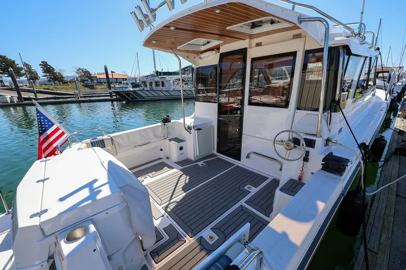 Slide: The Image of 2019 Cutwater C-302 Coupe docked, showcasing spacious deck and American flag. - 2