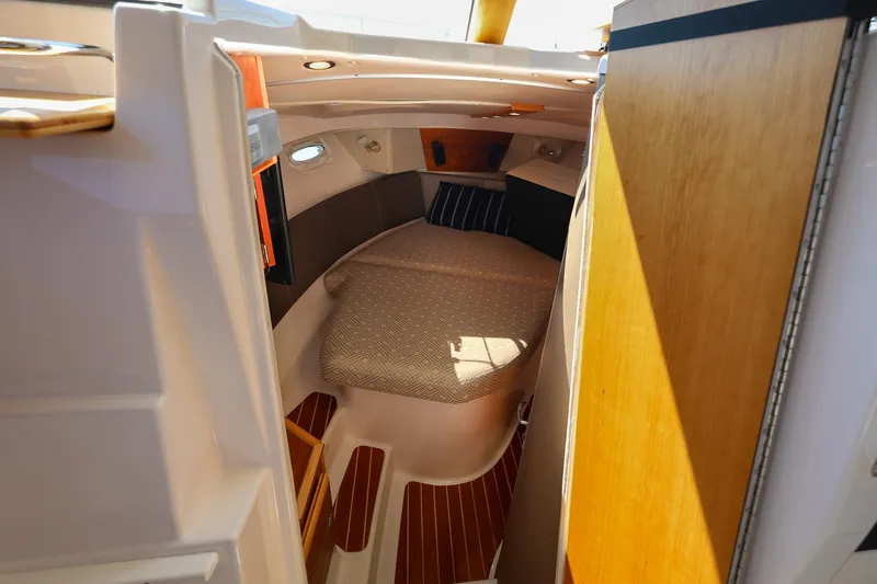 Slide: The Image of 2019 Cutwater C-302 Coupe cabin interior with cozy bed and wooden accents. - 24