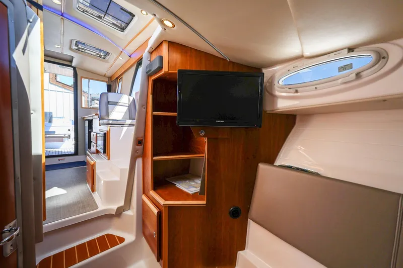 Slide: The Image of 2019 Cutwater C-302 Coupe interior with wood accents, seating, and mounted TV. - 26