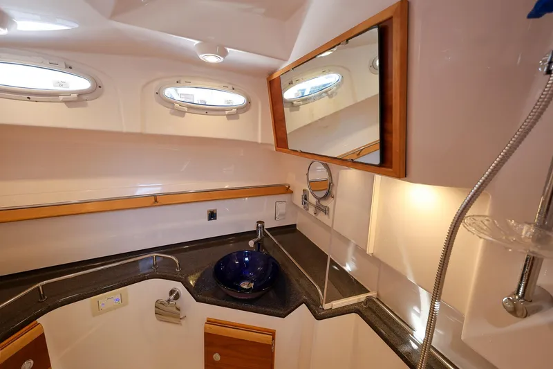 Slide: The Image of 2019 Cutwater C-302 Coupe bathroom with modern sink, mirror, and porthole windows. - 27