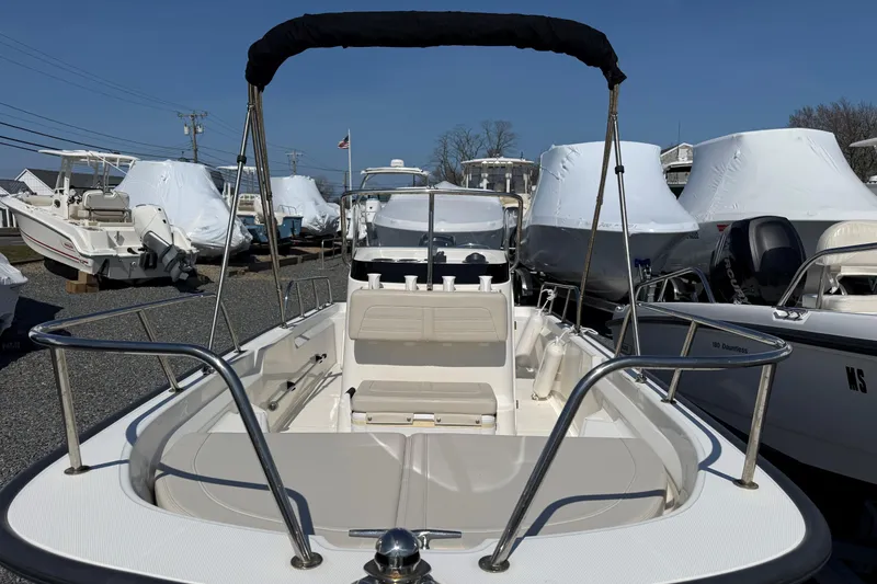Slide: The Image of 2018 Boston Whaler 150 Montauk boat with bimini top, docked among other boats. - 3