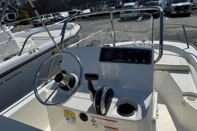 Slide: The Image of 2018 Boston Whaler 150 Montauk boat dashboard with steering wheel and controls. - 6