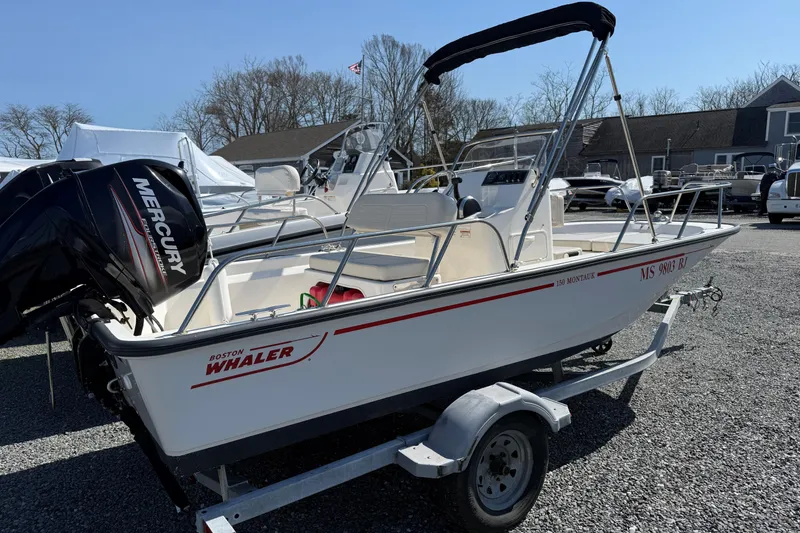 Slide: The Image of 2018 Boston Whaler 150 Montauk boat with Mercury engine on trailer, parked outdoors. - 8