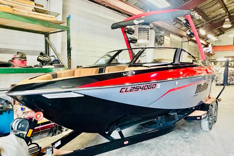 The Image of 2023 Malibu Wakesetter 23 LSV boat in a garage, featuring sleek black and red design. - 1