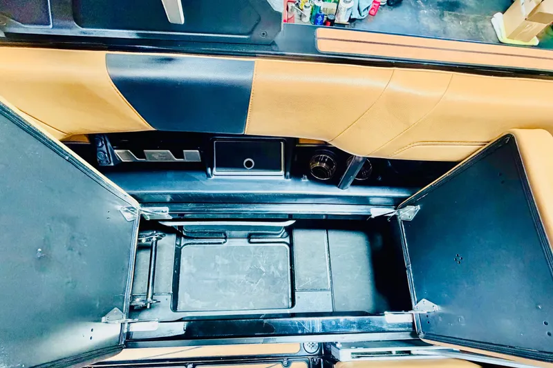 Slide: The Image of 2023 Malibu Wakesetter 23 LSV interior storage compartment with tan and black upholstery. - 14