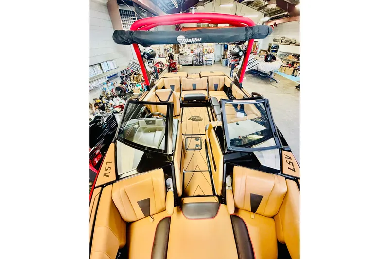 Slide: The Image of 2023 Malibu Wakesetter 23 LSV boat interior with tan seating and red accents in a showroom. - 22