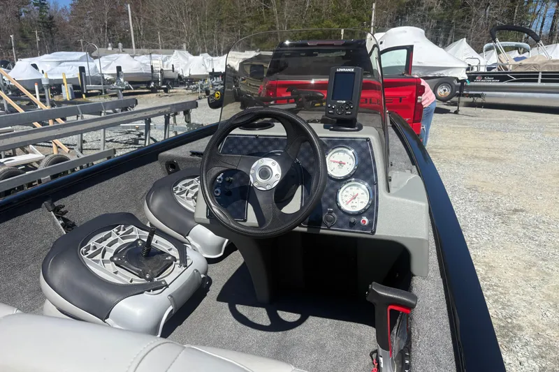 Slide: The Image of 2018 Tracker Pro 160 boat interior with steering wheel and gauges, parked outdoors. - 2