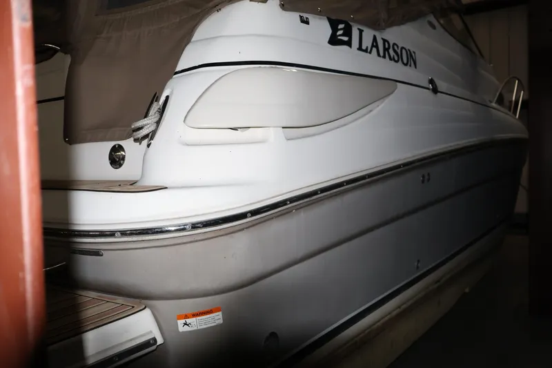 Slide: The Image of 2006 Larson Cabrio 240 boat, white exterior, partially covered, docked indoors. - 25