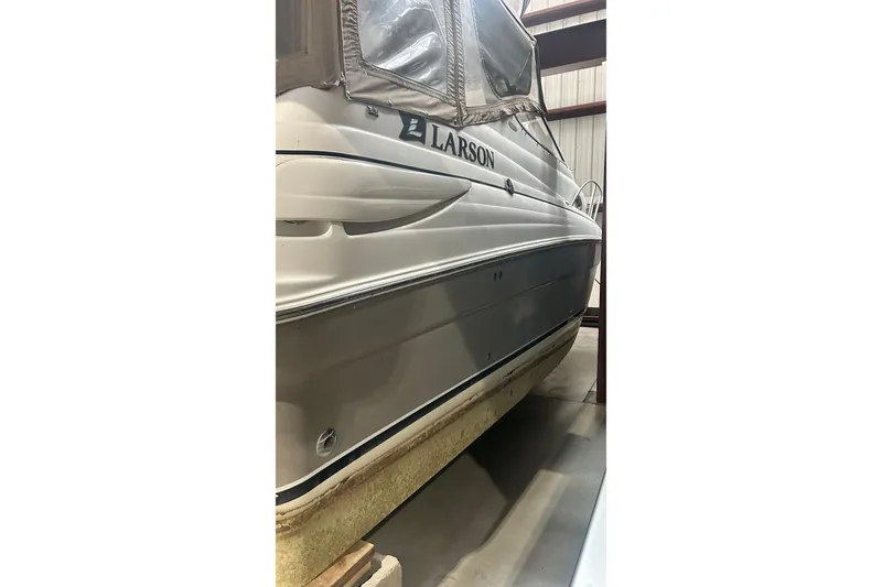 Slide: The Image of 2006 Larson Cabrio 240 boat in storage, side view with visible branding. - 27