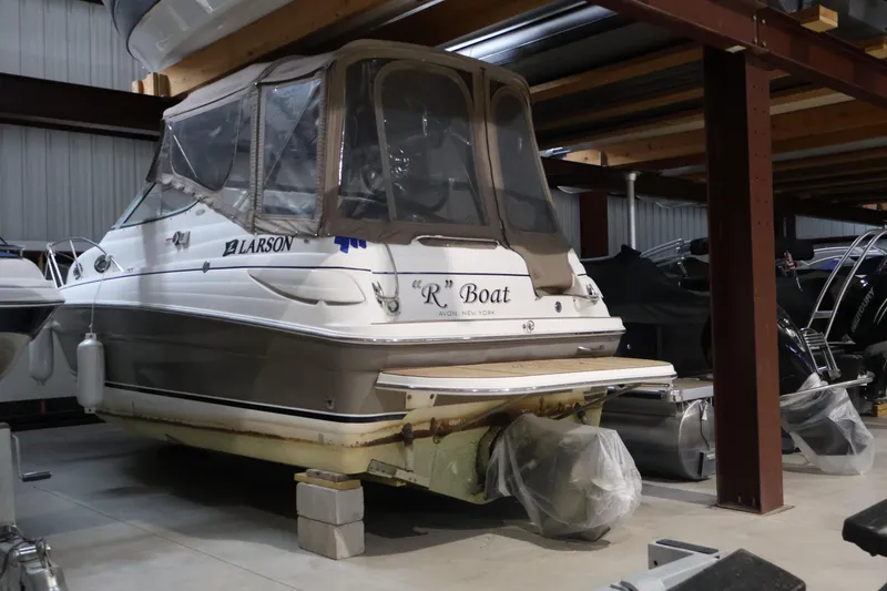 Slide: The Image of 2006 Larson Cabrio 240 boat stored indoors, featuring a covered cockpit and sleek design. - 3