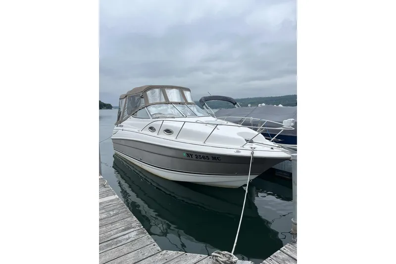 Slide: The Image of 2006 Larson Cabrio 240 boat docked on a calm lake under cloudy skies. - 30