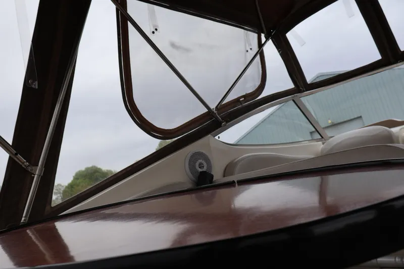 Slide: The Image of 2006 Larson Cabrio 240 boat interior with wood finish and canopy view. - 34