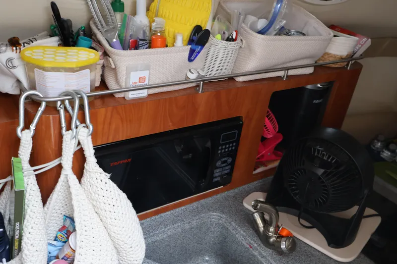 Slide: The Image of Compact kitchen area in a 2006 Larson Cabrio 240 boat with organized storage and appliances. - 39