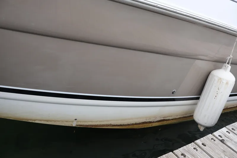 Slide: The Image of 2006 Larson Cabrio 240 boat hull with fender, docked at marina. - 44