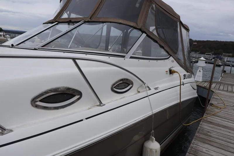 Slide: The Image of 2006 Larson Cabrio 240 boat docked at marina with brown canopy. - 45