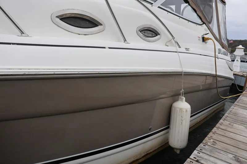 Slide: The Image of 2006 Larson Cabrio 240 boat docked, featuring sleek design and protective fender. - 46