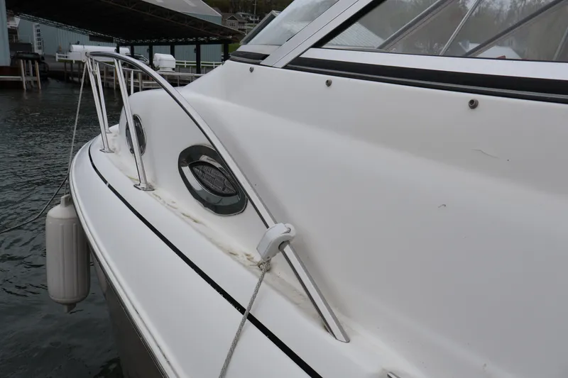Slide: The Image of 2006 Larson Cabrio 240 boat docked, showing side view with porthole and railing. - 47