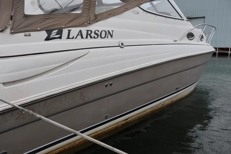 Slide: The Image of 2006 Larson Cabrio 240 boat docked, featuring sleek white and gray exterior design. - 48