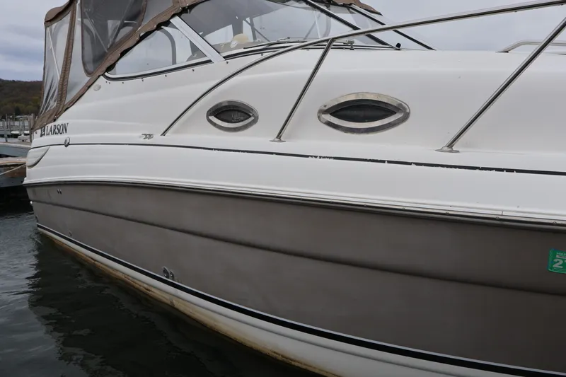 Slide: The Image of 2006 Larson Cabrio 240 boat docked, featuring sleek design and porthole windows. - 49