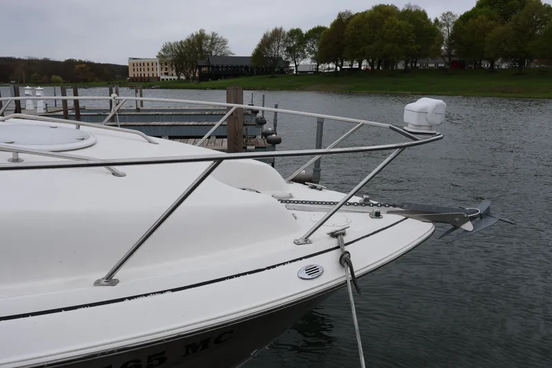 Slide: The Image of 2006 Larson Cabrio 240 boat docked by a serene lakeside with lush greenery. - 51