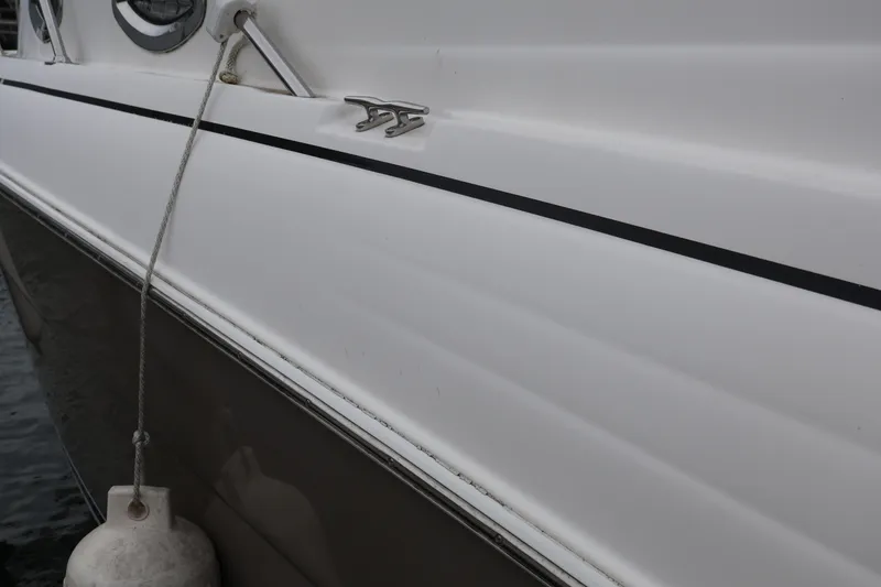 Slide: The Image of 2006 Larson Cabrio 240 boat side view with dock line and fender. - 55