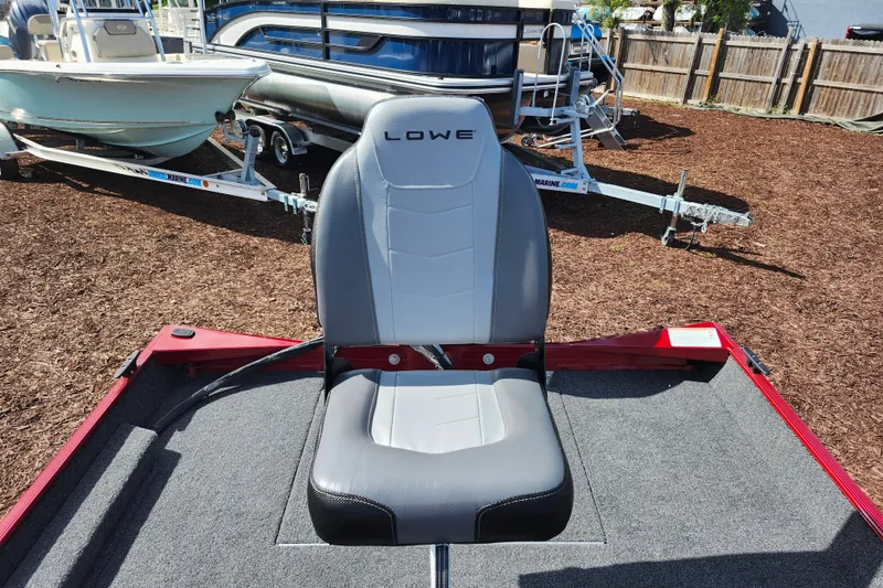 Slide: The Image of 2026 Lowe Skorpion 17 boat seat, gray upholstery, outdoor display with trailers in background. - 17