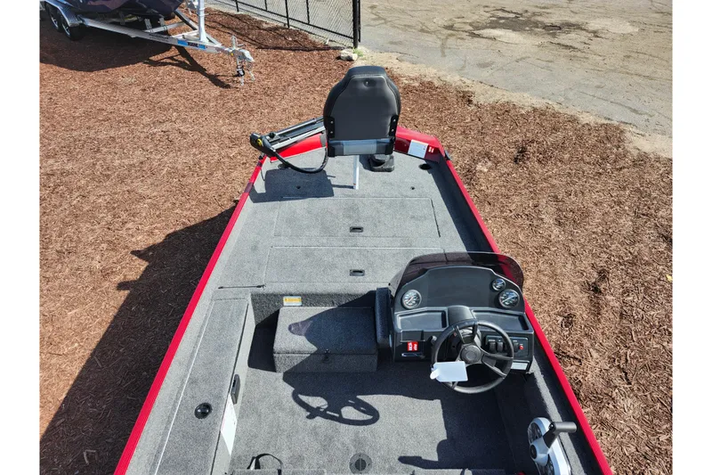 Slide: The Image of 2026 Lowe Skorpion 17 boat interior with steering console and seating, parked on mulch. - 25