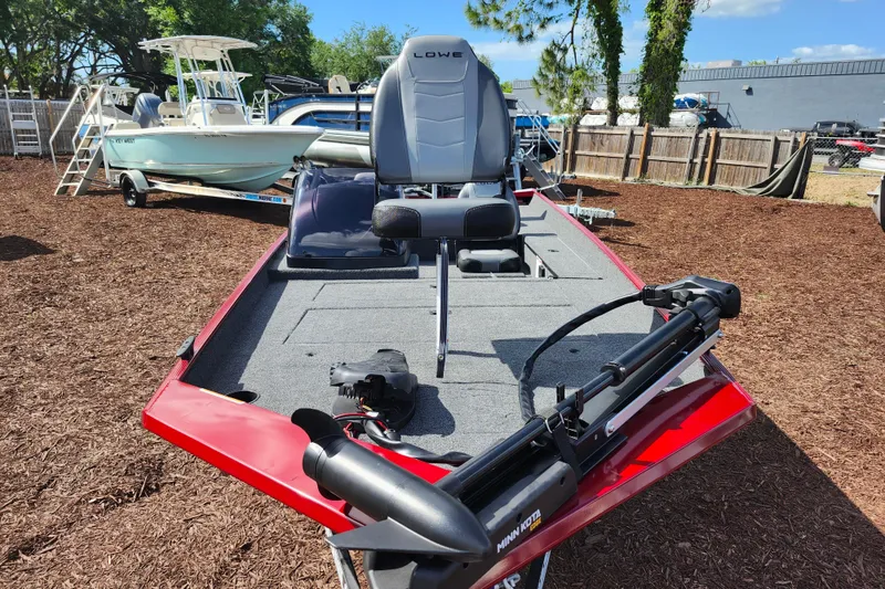 Slide: The Image of 2026 Lowe Skorpion 17 fishing boat with red exterior and trolling motor, parked outdoors. - 9