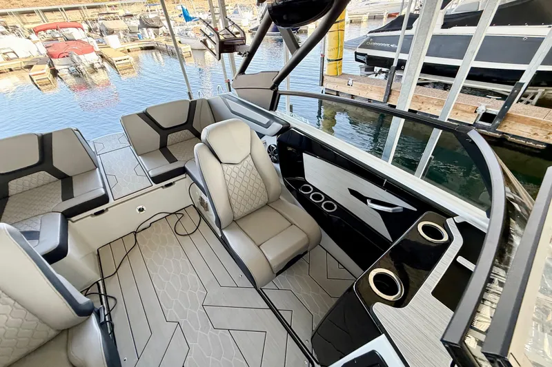 Slide: The Image of 2024 Yamaha Boats 222XE interior with modern seating and sleek design at a marina. - 14