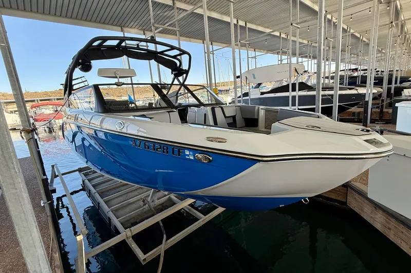 Slide: The Image of 2024 Yamaha Boats 222XE in marina, blue and white design, docked under shelter. - 17