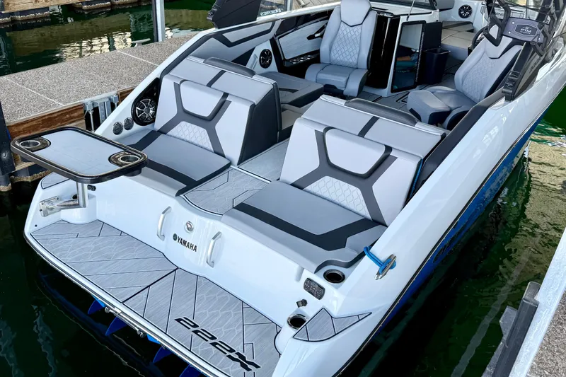 Slide: The Image of 2024 Yamaha Boats 222XE with sleek seating and modern design at a dock. - 2