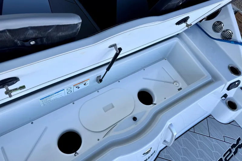 Slide: The Image of 2024 Yamaha Boats 222XE storage compartment with cup holders and seating area. - 23